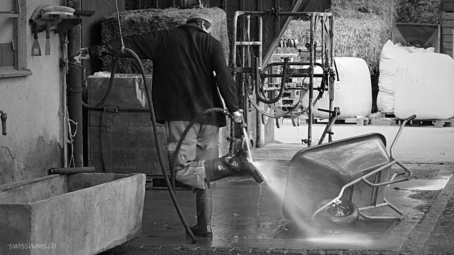 Der Bauer im Werkheim Wyden vom Rhyboot in Balgach spritzt seine Stiefel ab