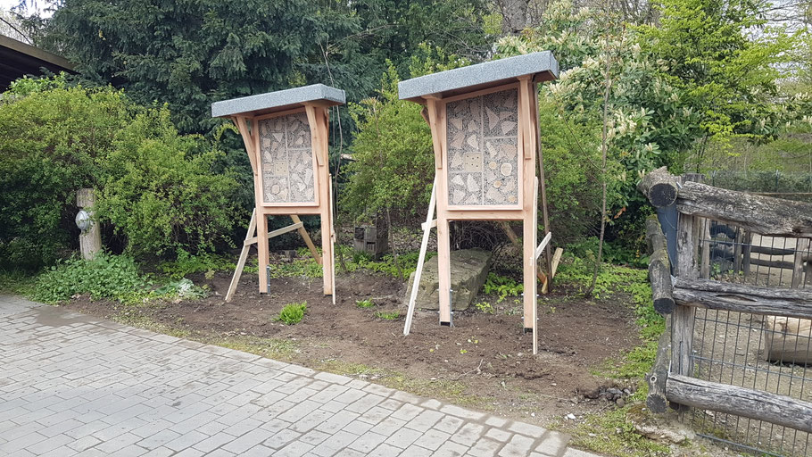 Neu aufgebaute Bienen Hotels, zwei Stück groß mit 2 Ständern in einem Beet.