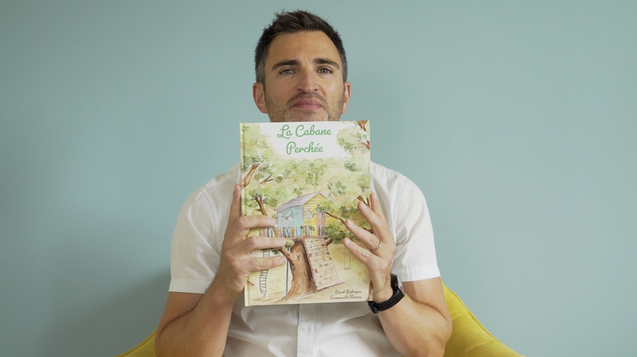 Portrait de David Rodrigues avec son livre jeunesse La Cabane Perchée, un projet de sensibilisation à la santé mentale