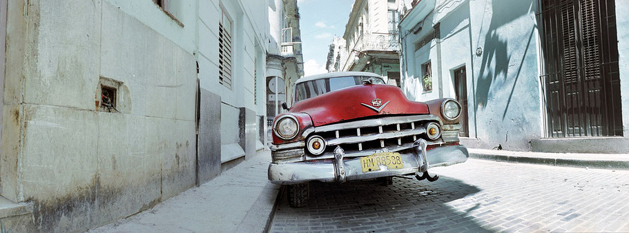 Roter Oldtimer ohne Vorderrad steht auf der Straße in der Altstadt von Havanna als Farbphoto im Panoramaformat, Cuba