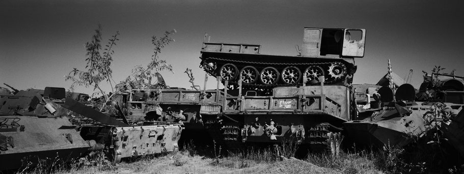 Kriegsschrott aufgetürmt als Mauer im Tank Graveyard in Asmara, Eritrea, als Schwarzweißphoto im Panorama-Format