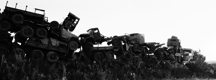 Kriegsschrott aufgetürmt als Mauer im Tank Graveyard in Asmara, Eritrea, als Schwarzweißphoto im Panorama-Format