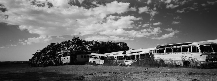 Kriegsschrott aufgetürmt als Mauer im Tank Graveyard in Asmara, Eritrea, als Schwarzweißphoto im Panorama-Format