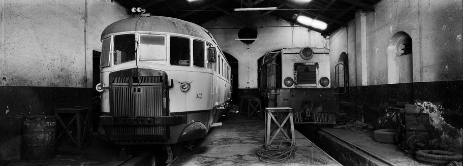Zwei alte Triebwagen in der Werkstatthalle der Asmara Ferrovia als Schwarzweißphoto im Panorama-Format