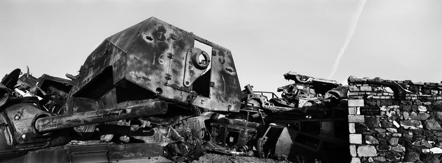 Kriegsschrott aufgetürmt als Mauer im Tank Graveyard in Asmara, Eritrea, als Schwarzweißphoto im Panorama-Format
