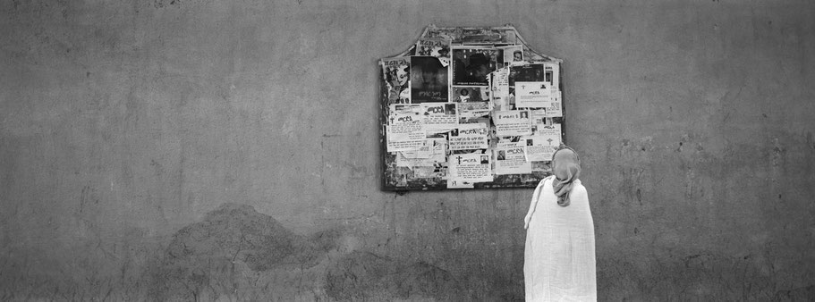 Alte Frau vor Wandzeitung in der Harnet Avenue in Asmara, Eritrea, als Schwarzweißphoto im Panorama-Format