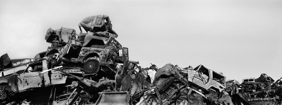 Kriegsschrott aufgetürmt als Mauer im Tank Graveyard in Asmara, Eritrea, als Schwarzweißphoto im Panorama-Format