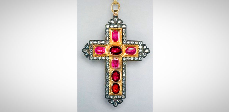 Ein Kreuz mit roten und rosa Steinen besetzt