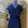Sur l'image, une robe portefeuille, évasée et à manches courtes faite en satin bleu pétrole. Création et réalisations uniques et sur mesure par la maison de couture Fil et Paillettes.
