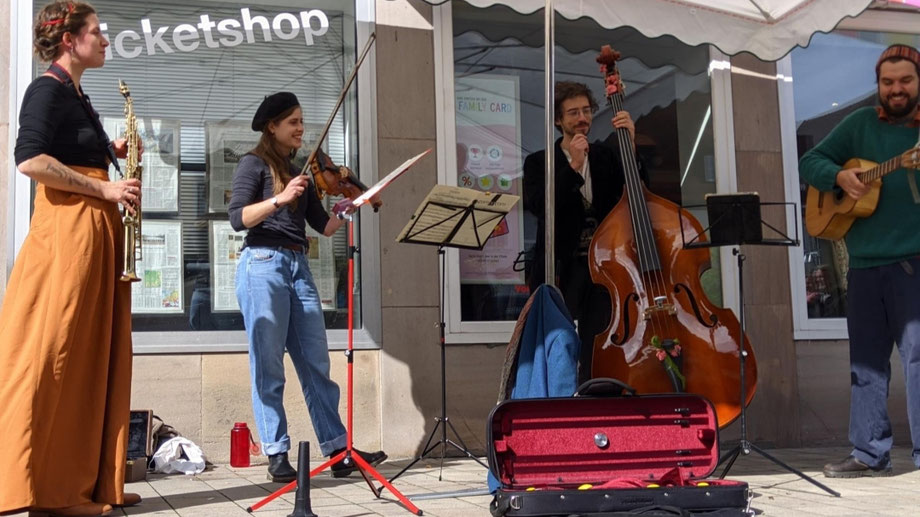 Das Quartett "Zitrönchen" spielt vor einem Laden mit unterschiedlichen Streich- und Blasinstrumenten: Sopransaxophonistin Maria Arvelase, Geigerin Elisabeth Hingerl, Gitarrist Folke Bo Blunck und Bassist Felix Wünsch.