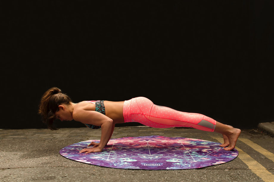 Eine Frau trainiert Liegestütze auf einer Yogamatte.