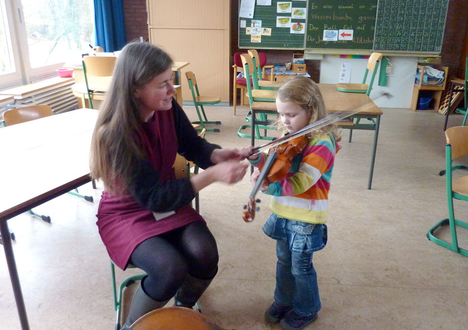 Heike Prange gibt einem interessierten Mädchen das erste Mal eine Geige in die Hand.