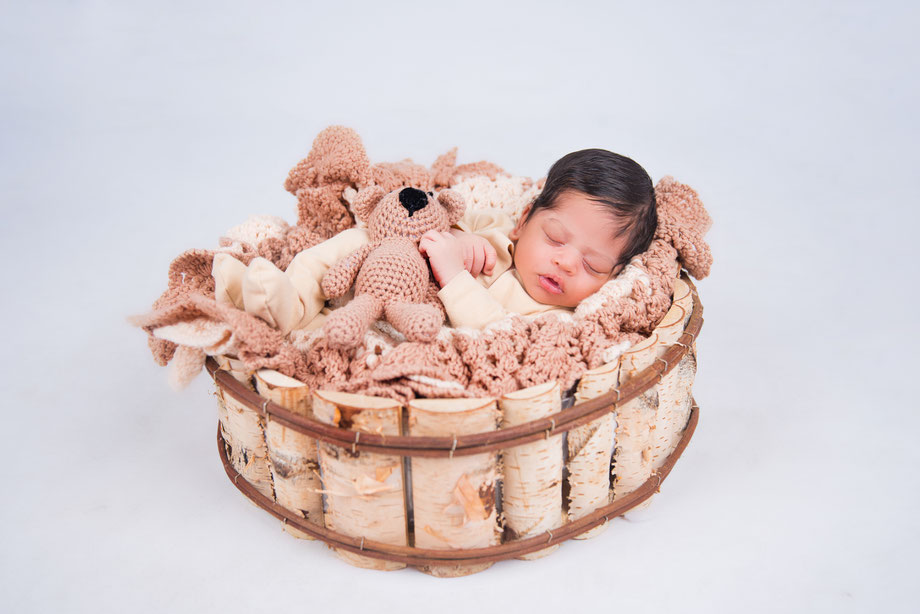 newborn in white dress holding teddybear