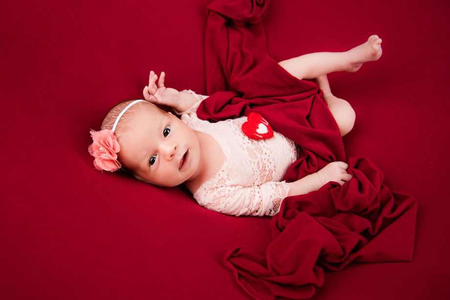 newborn girl with heart and in white dress