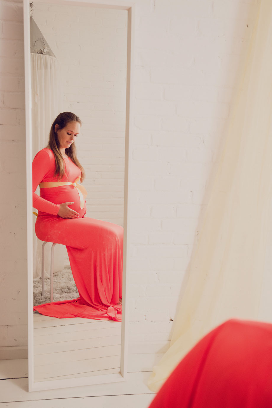zwangere vrouw in rode jurk in de spiegel