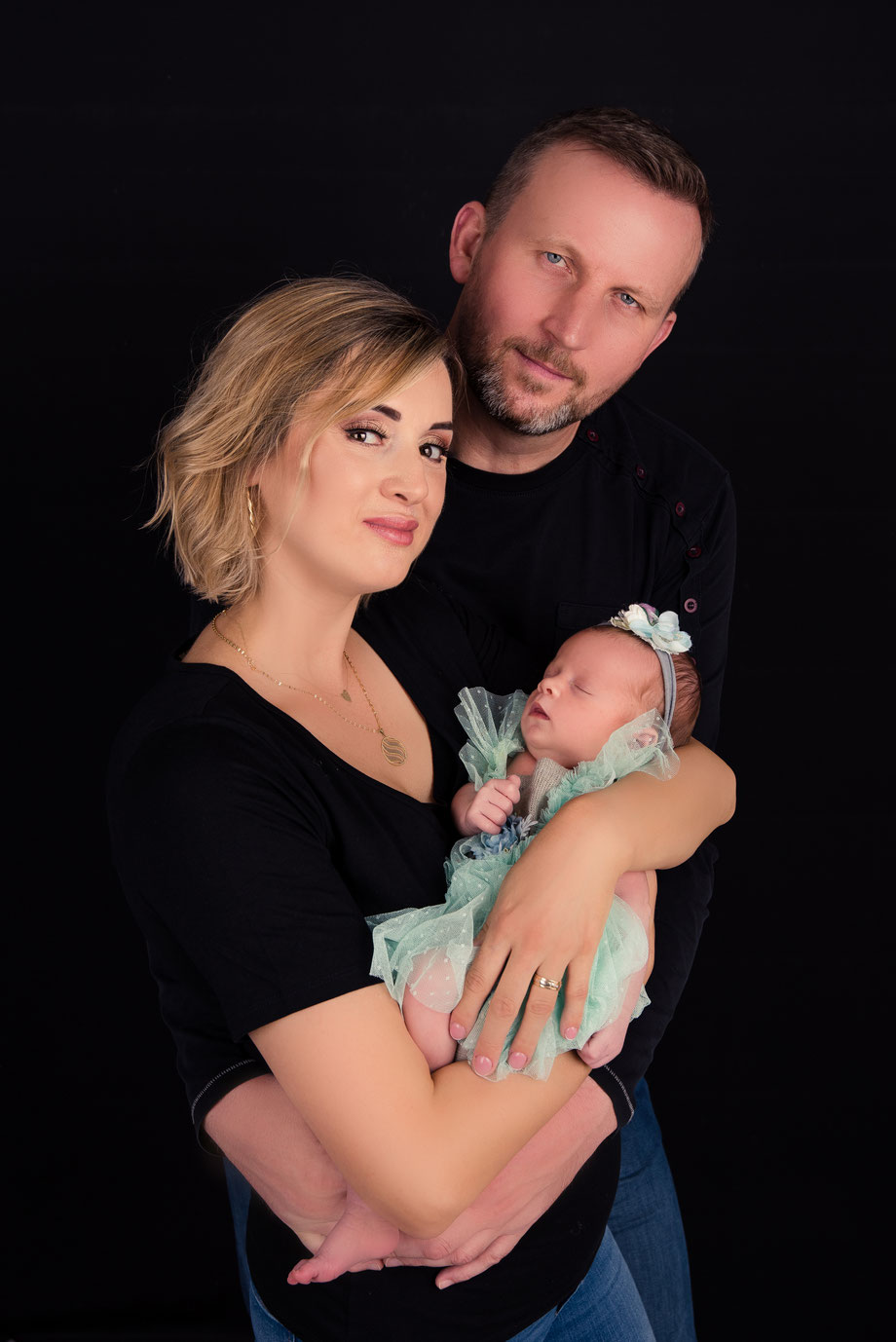 parents and newborn girl in green dress