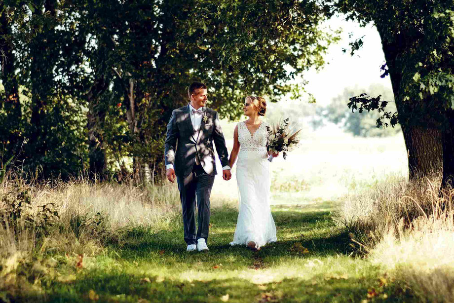 hochzeitsfotograf sendenhorst, fotoshooting hochzeit, braut und bräutigam gehen hand in hand durch einen wald