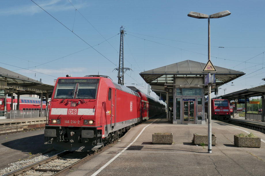 Ein roter Regionalzug in einem Bahnhof im Sonnenschein.