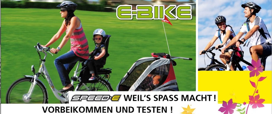 Eine Frau am E-Bike fahren in der Schweiz mit zwei Kindern, Kindersitz und Anhänger am Elektrovelo