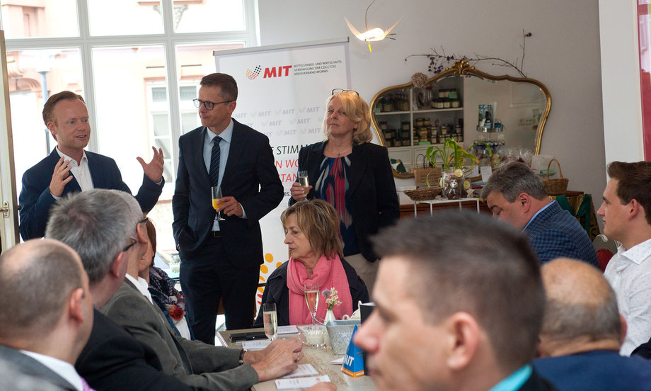 Der Bundestagsabgeordnete Jan Metzler, MIT Bundesvorsitzender Carsten Linnemann und die Wormser MIT Vorsitzende Iris Muth (stehend, von links) begrüßen zahlreiche Gäste.