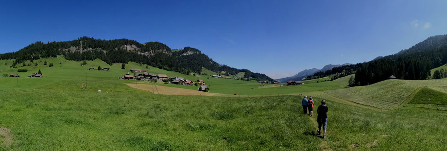 Wandern in schweizerischen Bergen über Felder, Hüel und vorbei an Bergdörfern