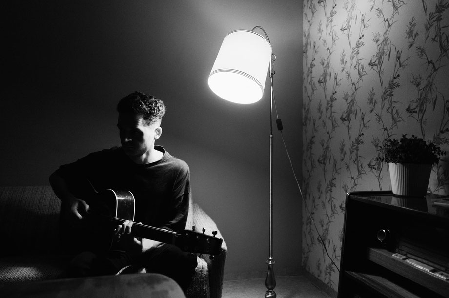 Schwarzweiß Stimmungsbild Gitarrist vor Lampe