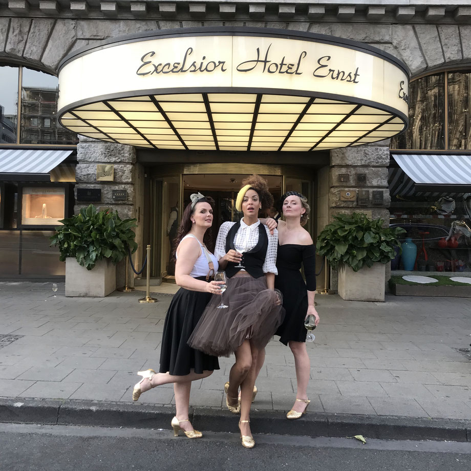 Julia Heiser, Lou Goldstein und Peggy Sugarhill von den Lou's The Cool Cats posen mit goldenen Schuhen vor dem Excelsior Hotel Ernst für ein Foto.