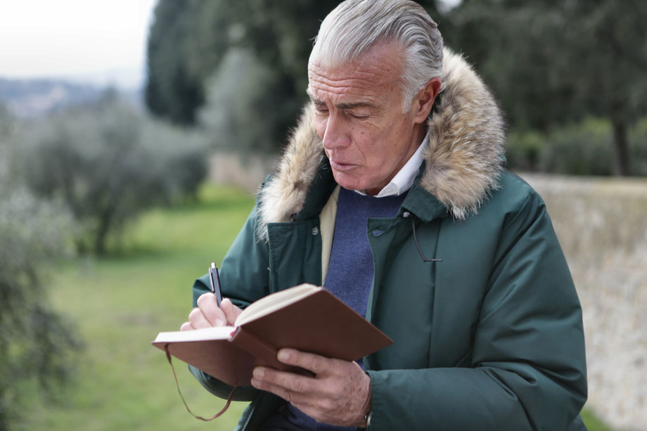 älterer Herr mit Notizbuch in der Natur