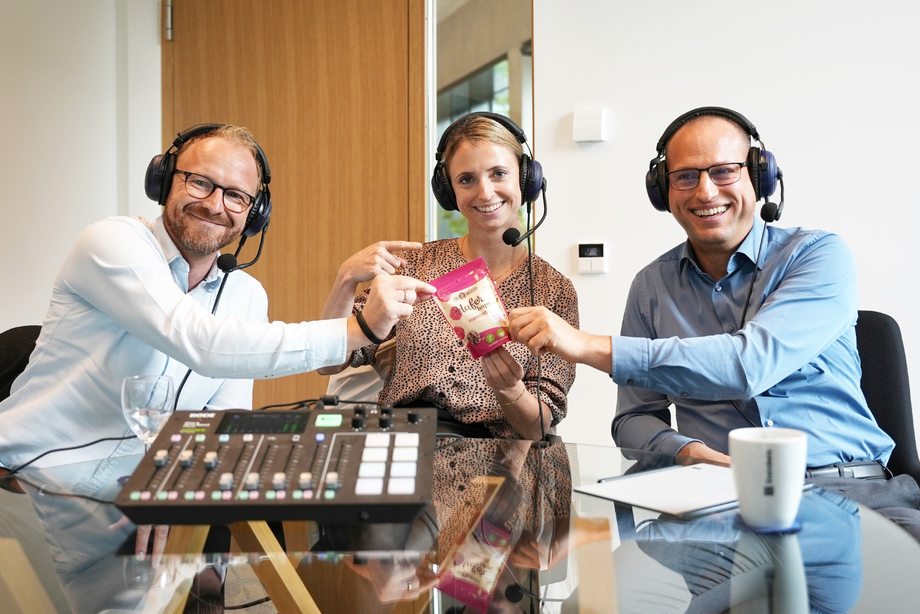 Mann und Frau mit Kopfhörern und Mikrofonen bei Pocast-Aufzeichnung mit Laptop und Notizblock