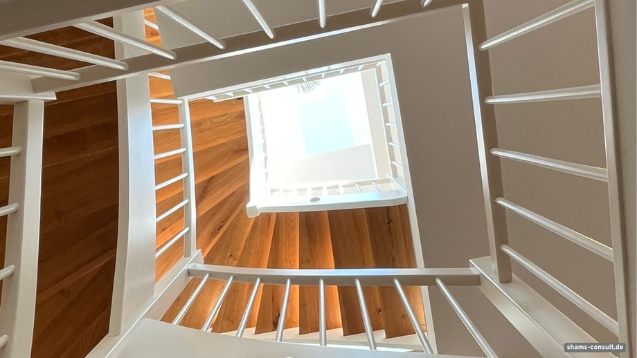 Holztreppe über mehrere Etagen mit Blick auf ein Dachfenster in der Mitte