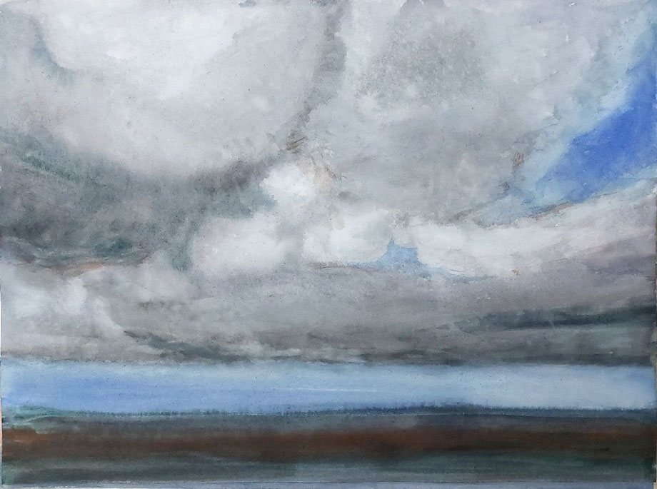 Cielo cubierto con nubes densas en tonos grises y azulados sobre un horizonte muy bajo de tierra y agua.