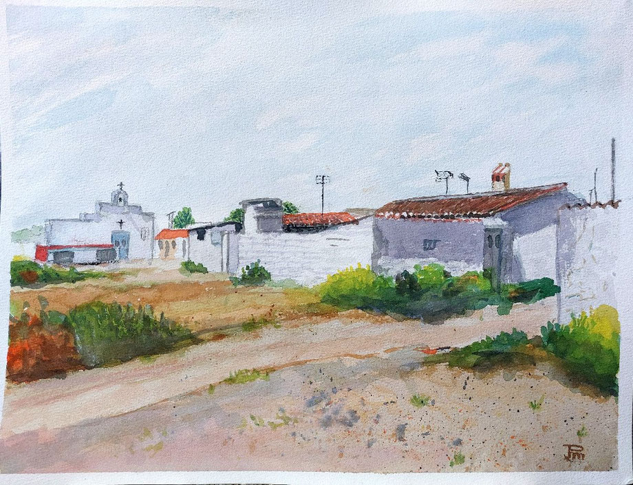 Casas blancas con tejados rojizos, camino de tierra, vegetación baja y una iglesia al fondo bajo cielo suave.