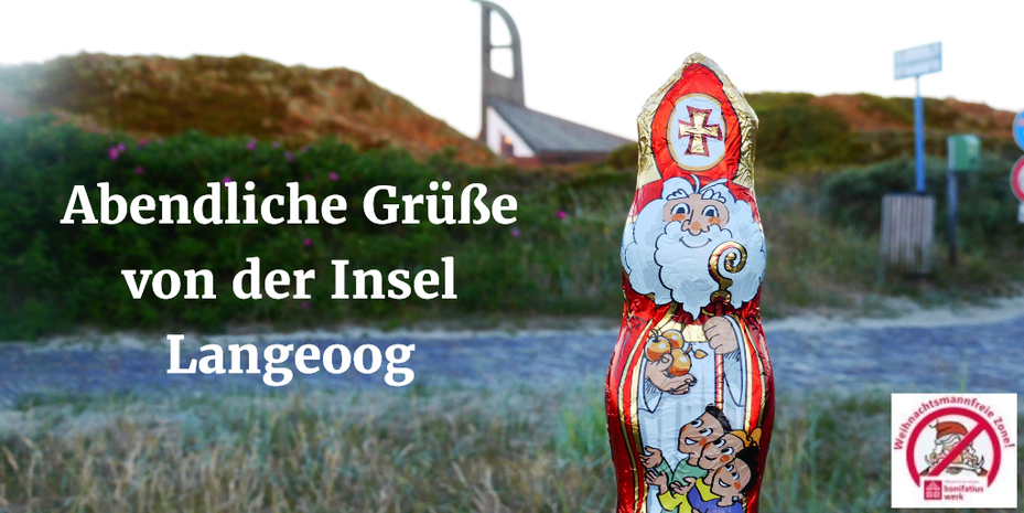 Der Schokonikolaus steht vor der St.-Nikolaus-Kirche auf Langeoog, die von Sanddünen umgeben ist.