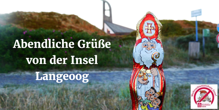 Der Schokonikolaus steht vor der St.-Nikolaus-Kirche auf Langeoog, die von Sanddünen umgeben ist. 