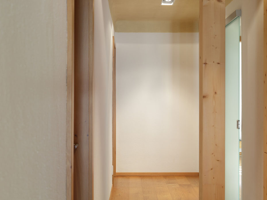 Vorraum mit Lehmfarbe in Marmorweiß an den Wänden, einer Decke in Camel, Holzrahmen und Holzboden.