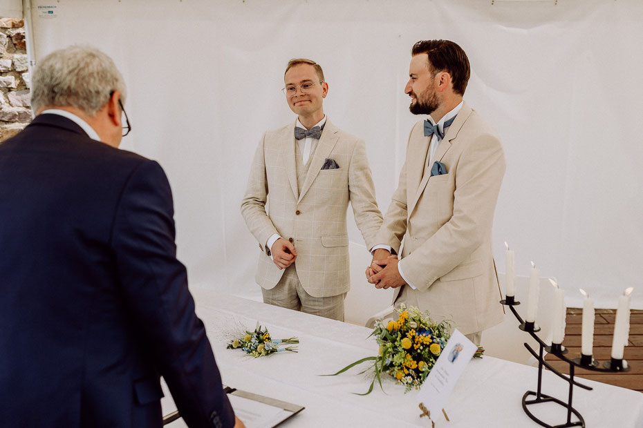 Bräutigamspaar steht nebeneinander und hält sich an den Händen während der Trauzeremonie