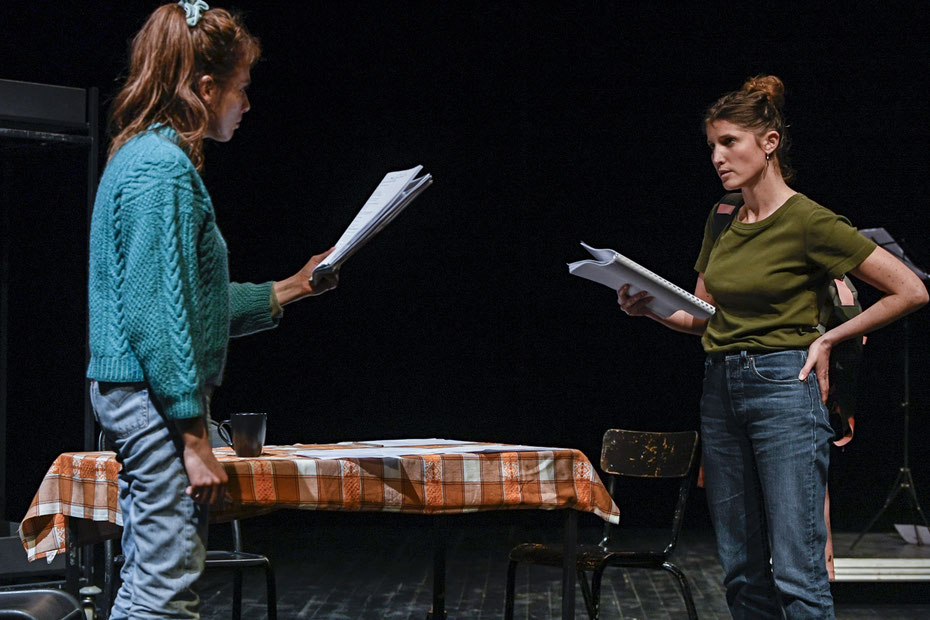 Photo des deux comédiennes de M'aime pas mort en répétition. Elles sont face à face avec leur texte en main.
