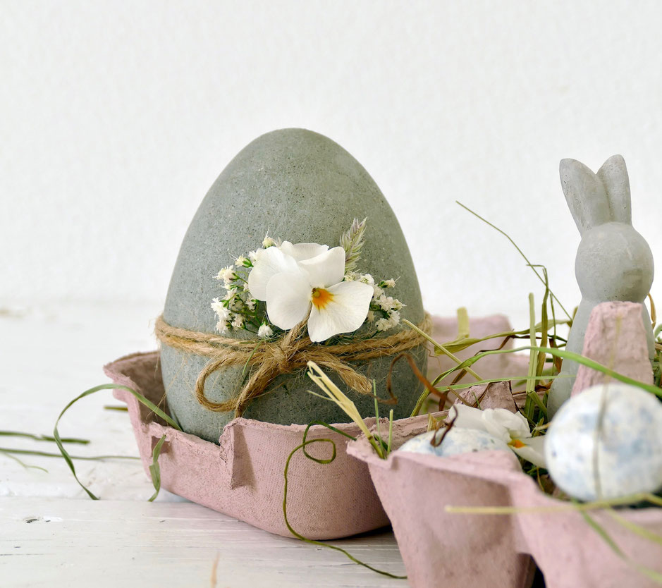 DIY Beton Osterei mit weisser Blume in rosa Eierschachtel mit Heu und kleinen Eiern