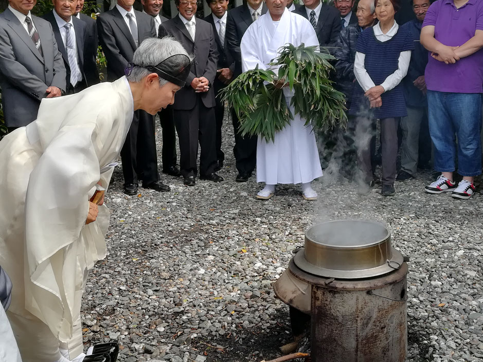 釜の前に立つ宮司さん。