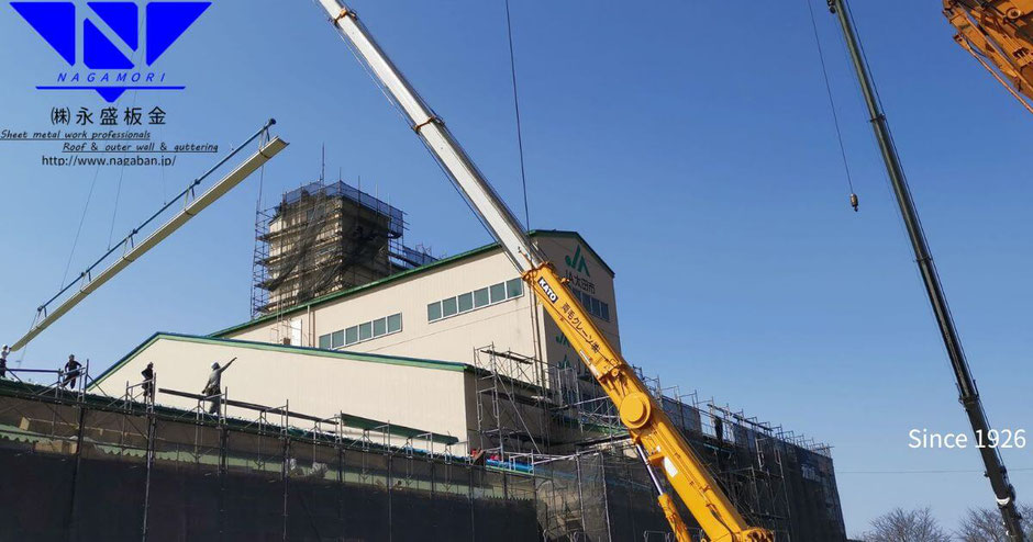 太田市内の工場で、ガルバリウム鋼板の折板屋根をレッカーで丁寧に荷揚げする様子。軽量で高強度な資材が建築を支えます。