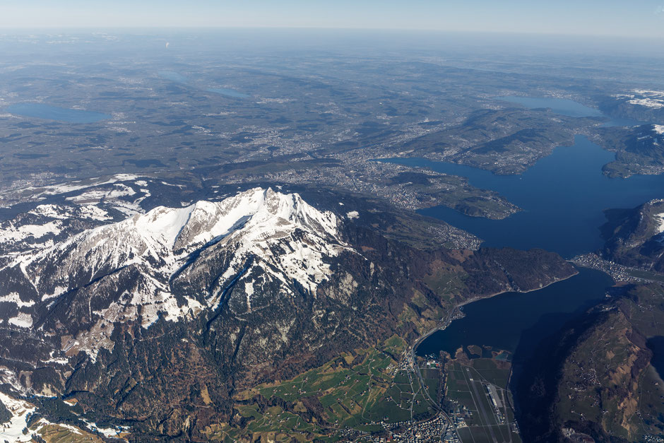 Der verschneite Gipfel des Pilatus überragt den Vierwaldstättersee und die malerische Stadt Luzern. In der Ferne ist bereits der Flughafen Zürich sichtbar.