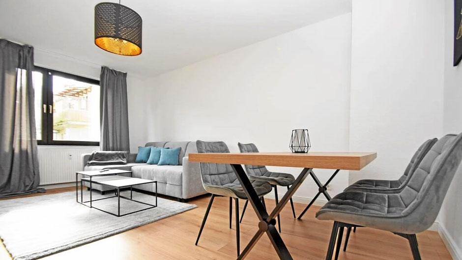 Modernes Wohnzimmer mit Sofa, Tisch und Stühlen im Air Apartment 1 in Bremen