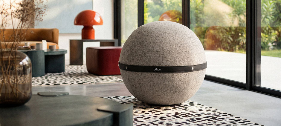Siège ballon Bloon au tissu moucheté disposé dans un salon lumineux, à côté d'un canapé, créant une ambiancece de décoration intérieure moderne et apaisante. Siège Ballon Bloon Dune ERGOaccessoires.com