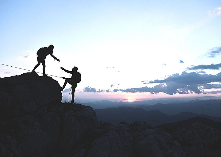 Ein Mann hält einer Frau die Hand hin, Bergpanorama,, Sonnenuntergang.