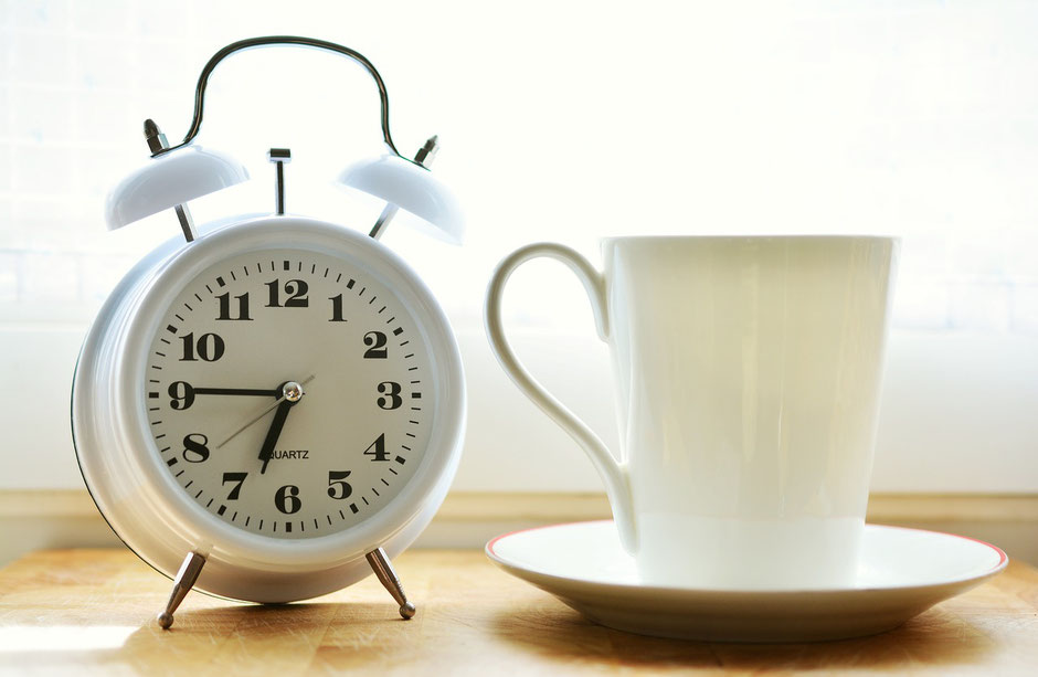 Coffee cup with an analogue clock next to it