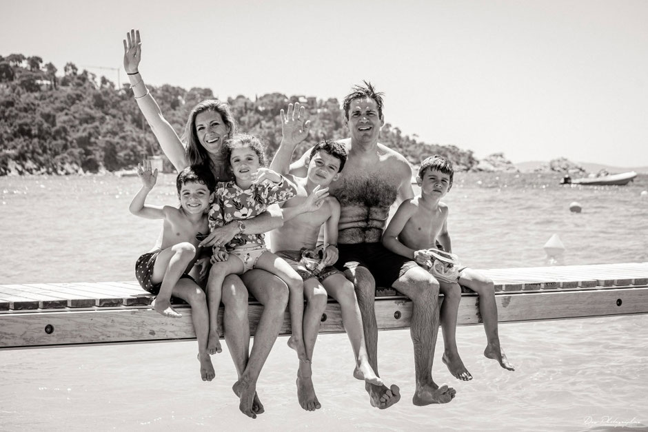 Family sitting on a wooden jetty by the sea during a holiday photoshoot in Saint-Tropez.