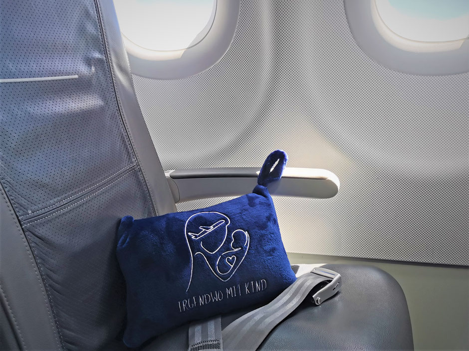 Ein dunkelblaues Kissen liegt auf einem Flugzeugstuhl.