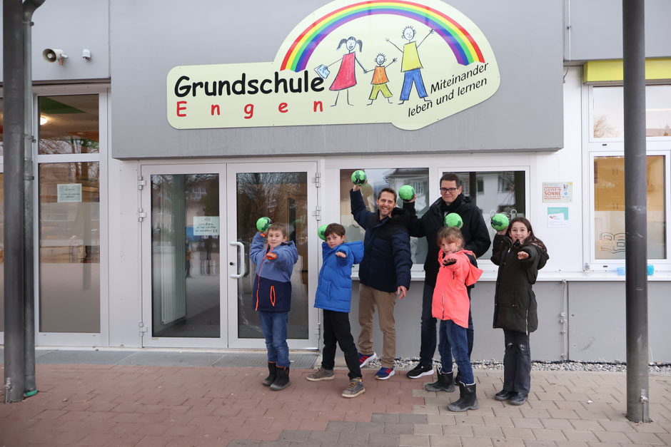 Schulleiter Holger Laufer und Jörg Ackermann freuen sich mit den Kindern über die neuen Handbälle