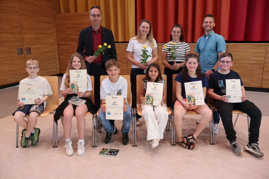 Im Vordergrund: Alle Teilnehmerinnen des diesjährigen Vorlesewettbewerbs; Im Hintergrund: die aktuelle Jury