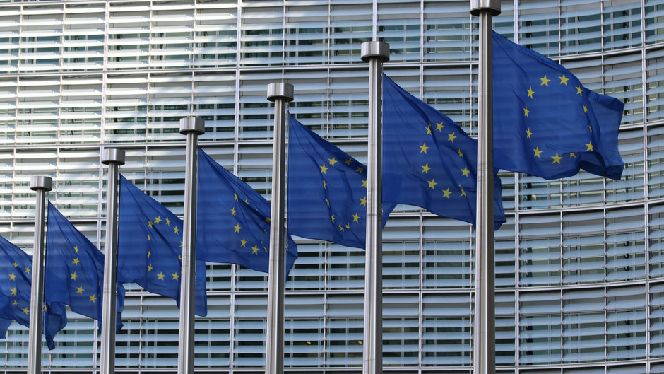 Flaggen vor dem Brüsseler Gebäude der EU-Kommission. Bild von Guillaume Perigois auf Unsplash. 